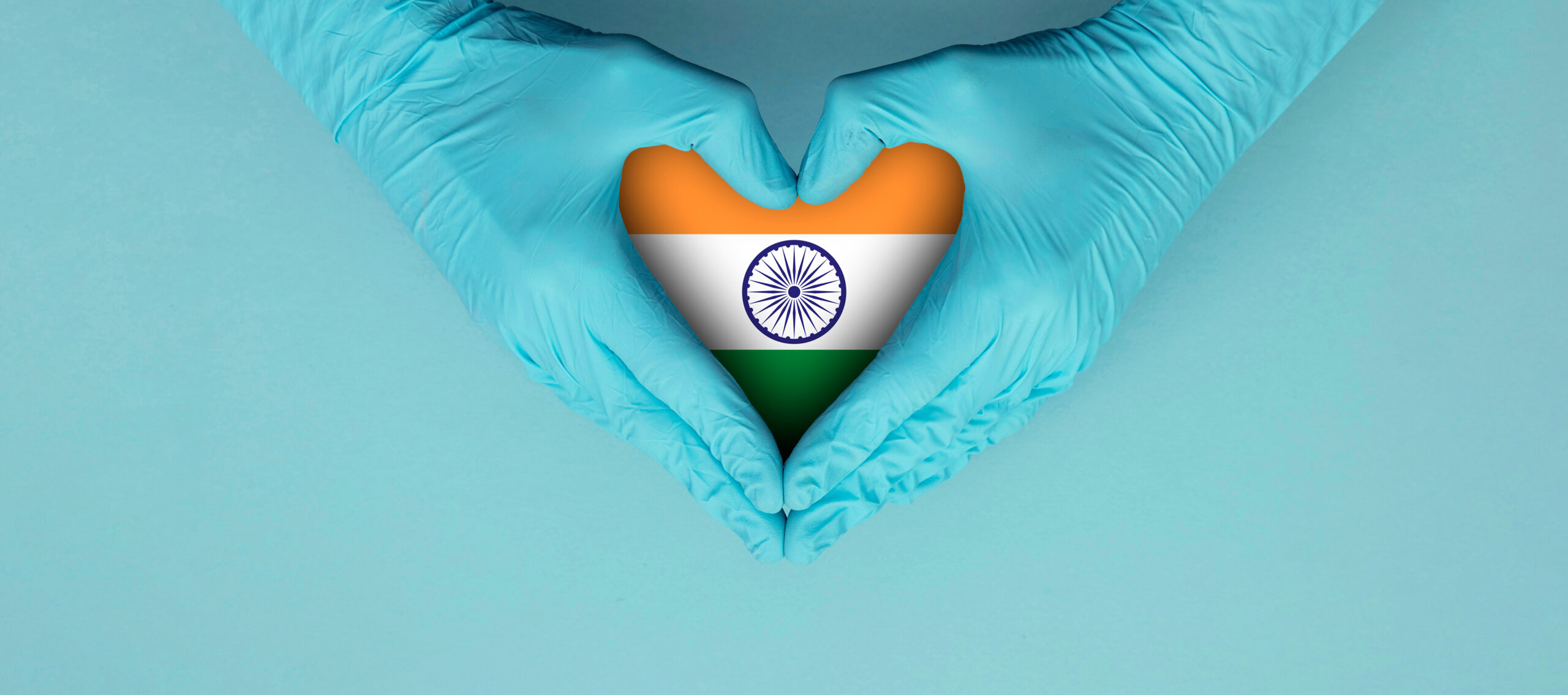 Doctors hands wearing blue surgical gloves making hear shape symbol with india flag